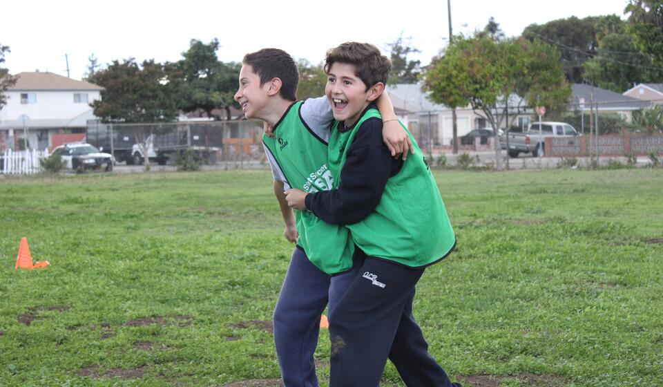 Two students laughing and having a wonderful time out in the soccer field.